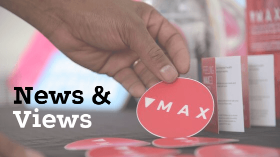 news and views of MAX Ottawa. Man picking up MAX sticker with MAX brochures in the background